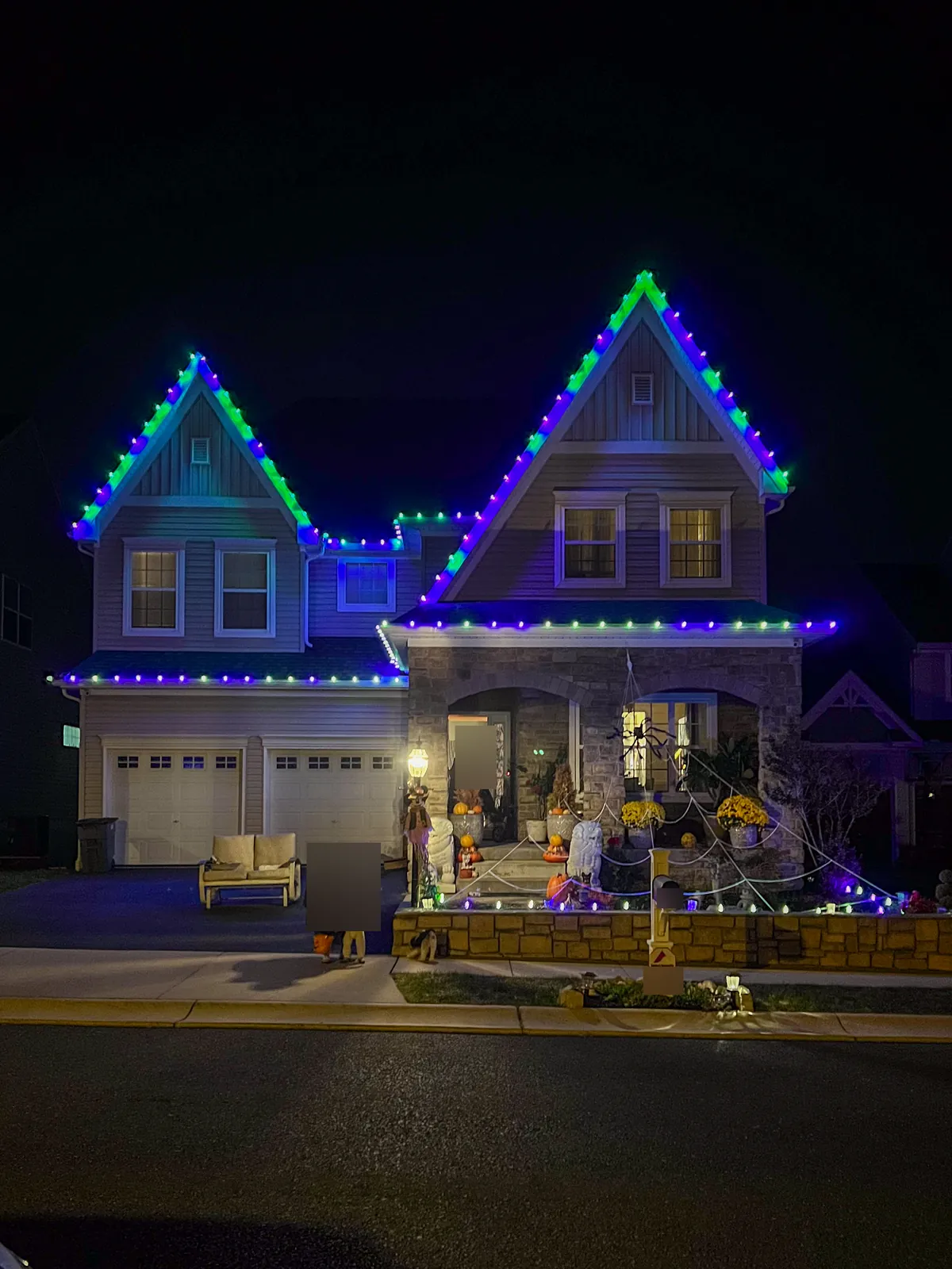 Permanent roofline lights in Roslyn set to green, blue and purple for Halloween on a two gable home